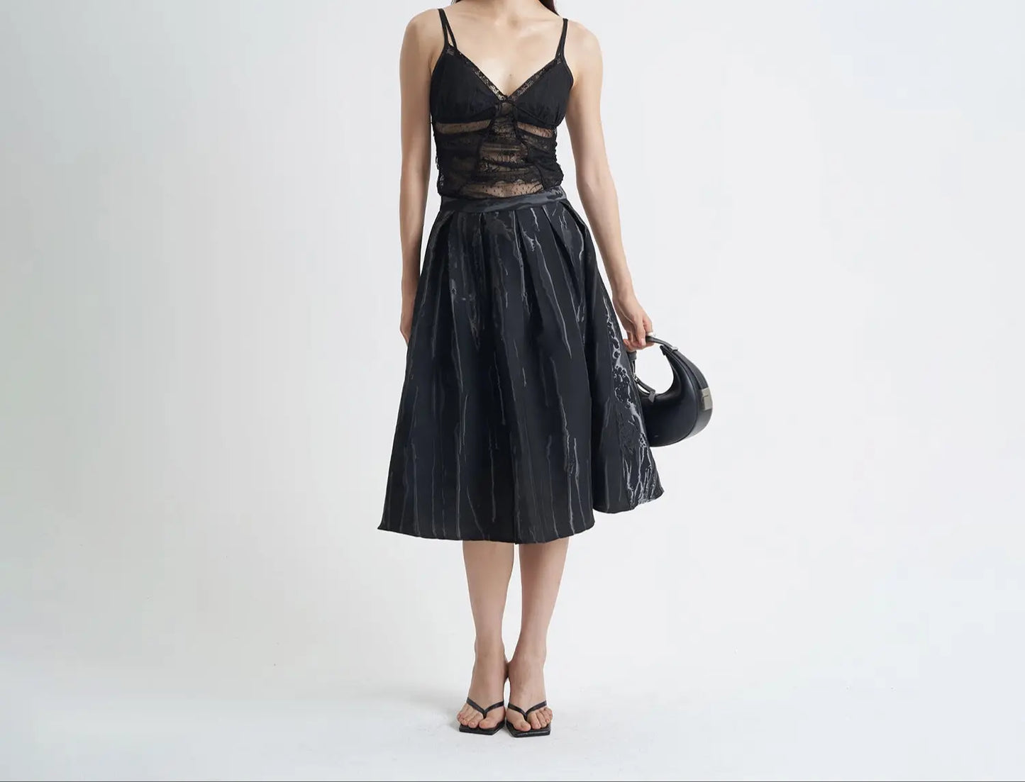 Jupe mi-longue noire à coupe évasée avec motifs 3D texturés, style chic et sobre, parfaite pour mettre en valeur la silhouette.