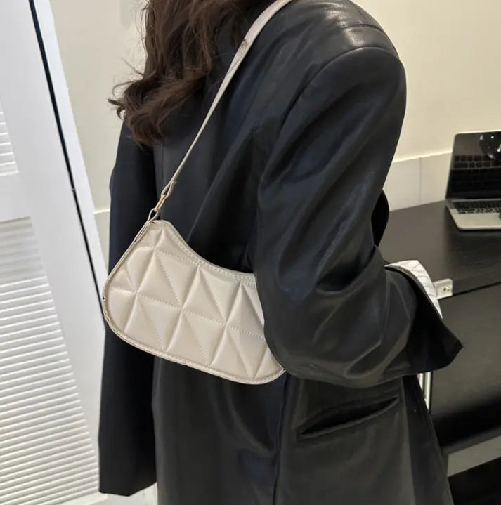 Sac bandoulière blanc porté à l’épaule, design élégant et pratique.