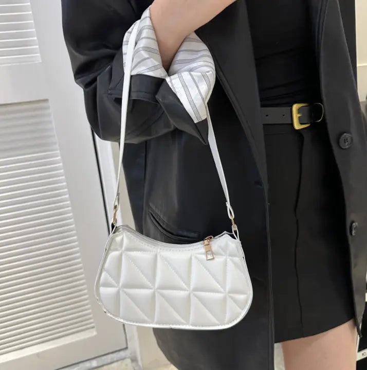 Sac bandoulière blanc porté à l’épaule, design élégant et pratique.