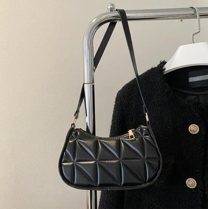 Sac bandoulière noir porté à l’épaule avec bandoulière ajustée.