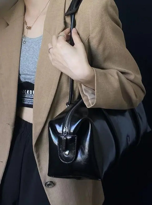 "Sac à main noir finition vernis, style simplicité urbaine"