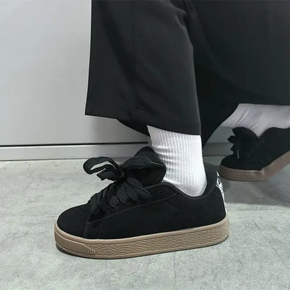 "Vue de profil des baskets streetwear chic noires femme semelle épaisse stable"