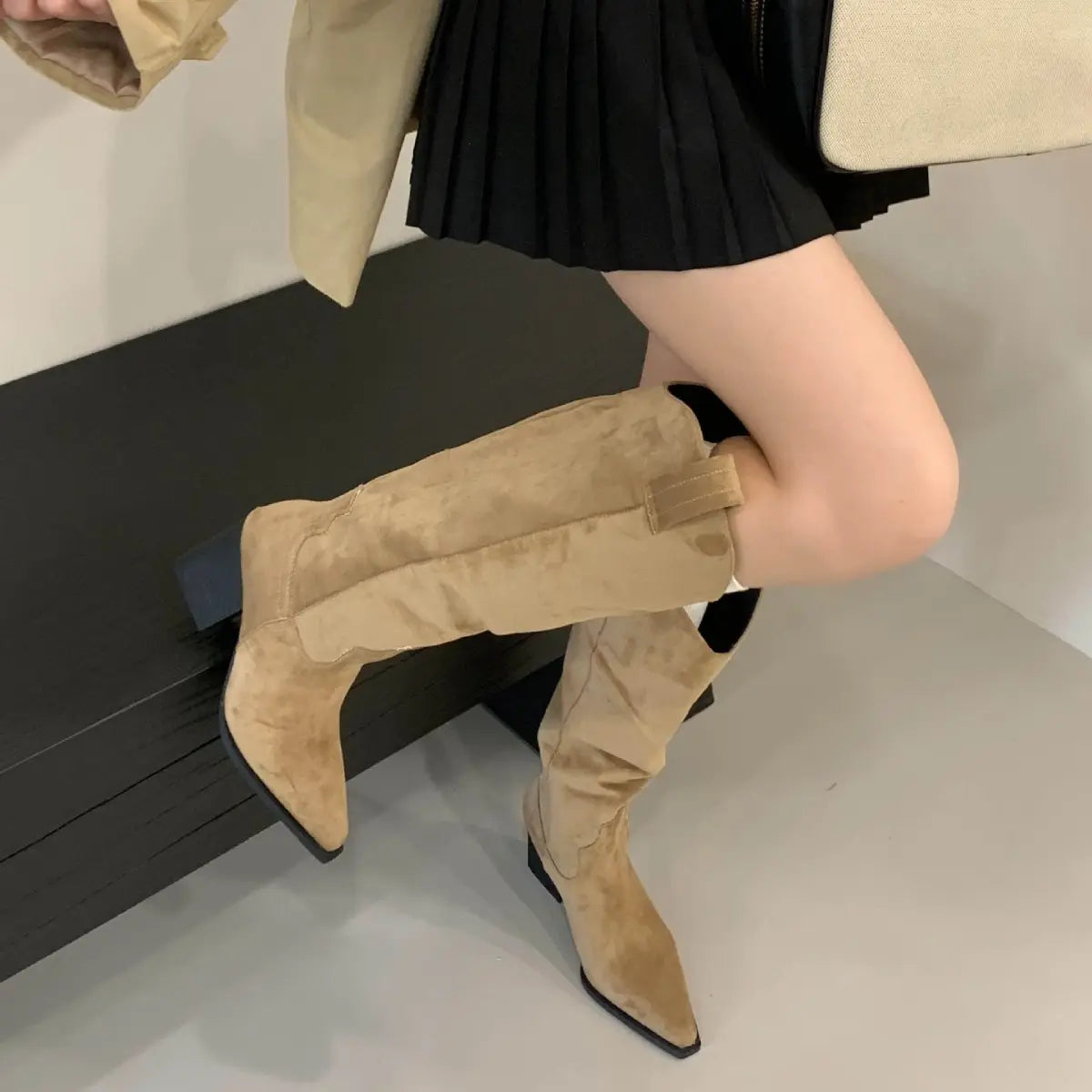 Bottes cowboy beiges femme portées avec une jupe noire
