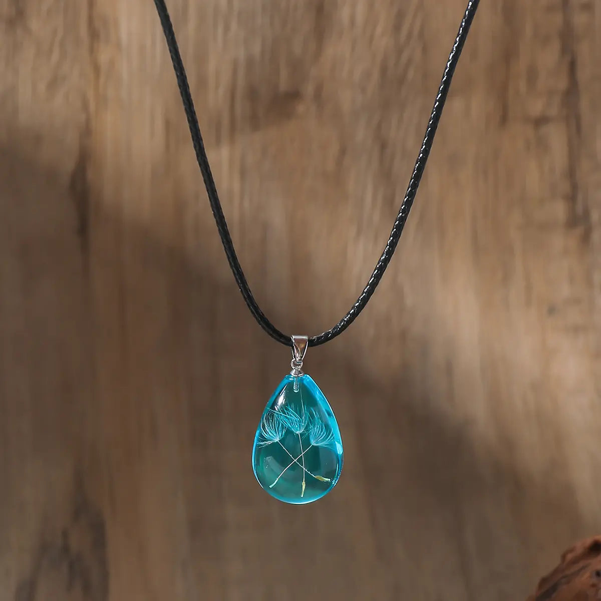 PBijoux artisanaux en résine transparente, design unique goutte avec fleur suspendue.
