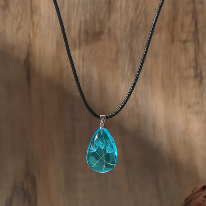 PBijoux artisanaux en résine transparente, design unique goutte avec fleur suspendue.