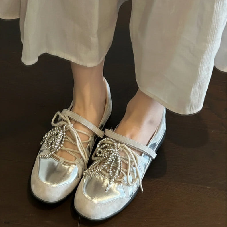 Chaussures plates dorées à lacets pour femme portées avec un pantalon blanc