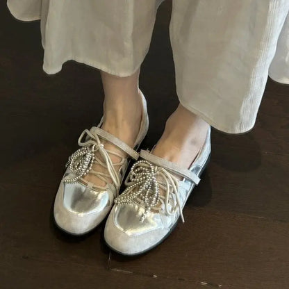 Détail de chaussures plates dorées pour femme avec lacets sur le dessus