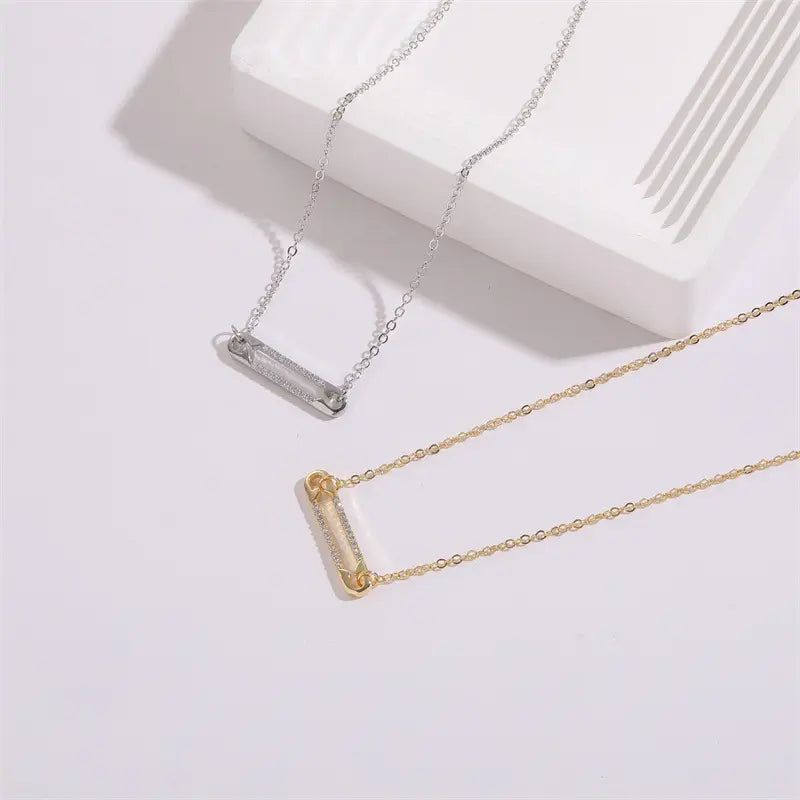 Collier minimaliste avec pendentif en forme d’épingle orné de zircons scintillants.