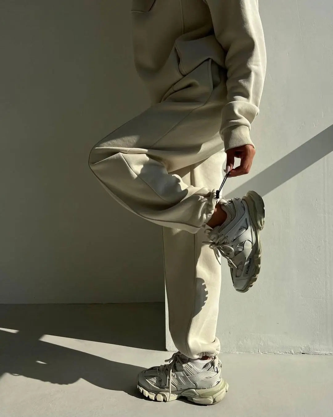 Ensemble streetwear femme composé d’un sweat manches longues col montant et d’un pantalon jogging décontracté, couleur crème, style chic et confortable