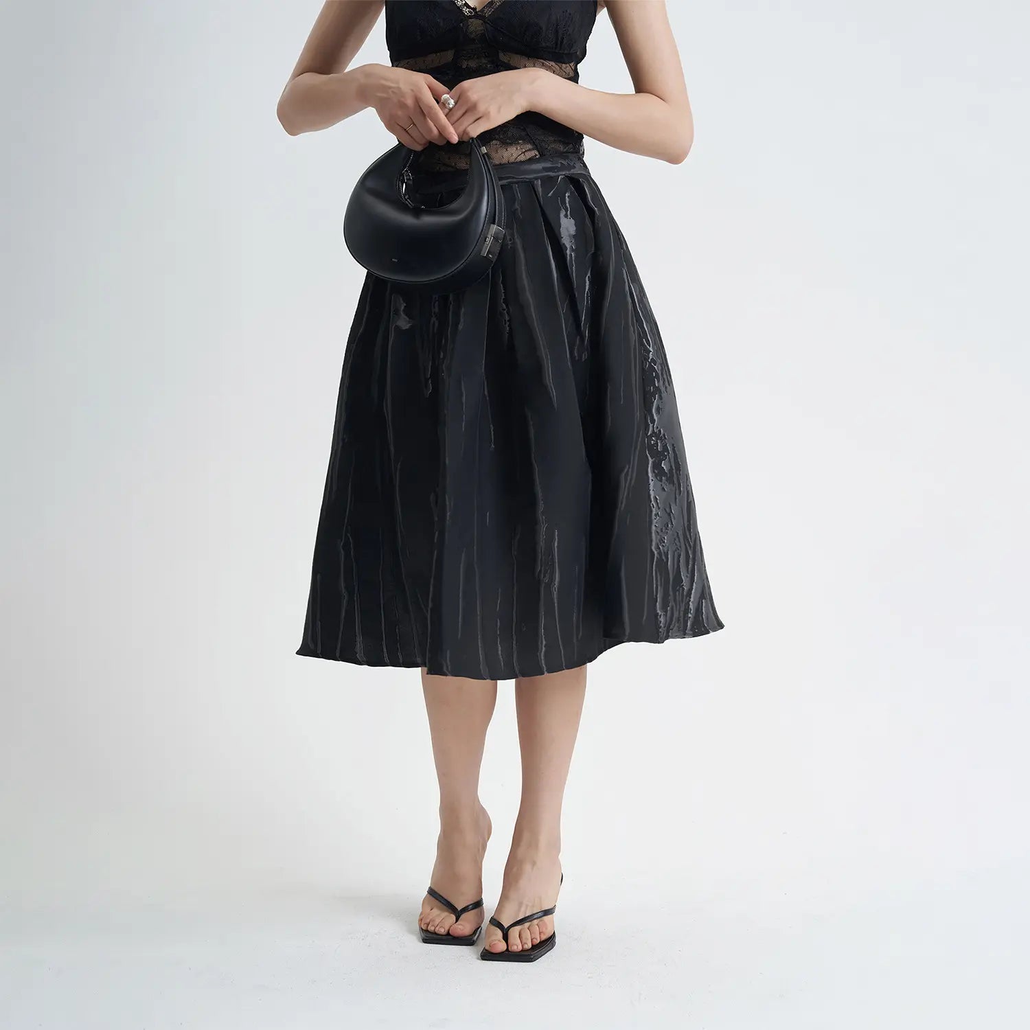 Jupe mi-longue noire chic en coton avec motifs 3D, coupe évasée confortable, idéale pour un look élégant et moderne.
