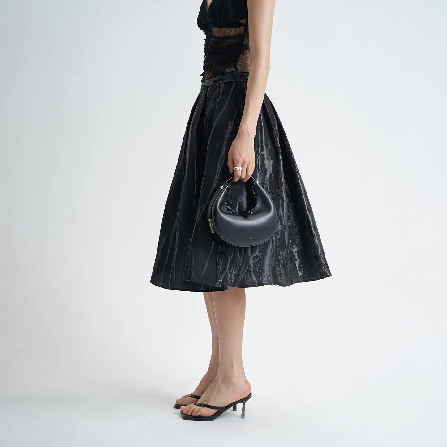 Jupe évasée noire mi-longue avec texture 3D, confection en coton de qualité, alliant confort et élégance.
