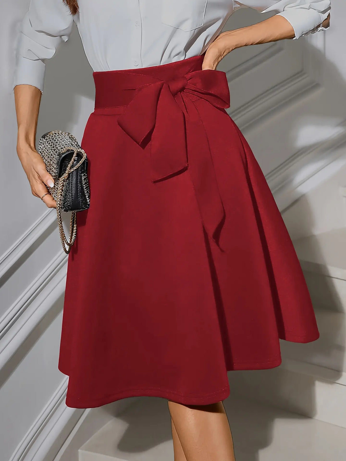 Jupe patineuse rétro chic noire et rouge avec nœud décoratif à la taille, tissu structuré, coupe élégante et confortable.