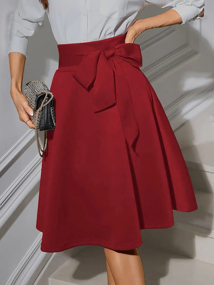 Jupe patineuse rétro chic noire et rouge avec nœud décoratif à la taille, tissu structuré, coupe élégante et confortable.
