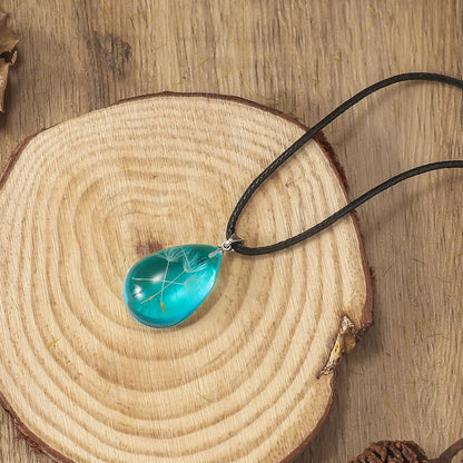 Ensemble collier et boucles d’oreilles goutte en résine, finition cristal et design aérien.