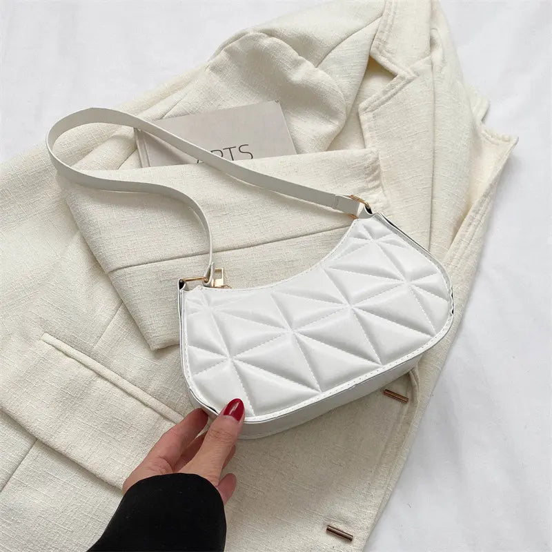 Sac bandoulière blanc porté à l’épaule, design élégant et pratique.