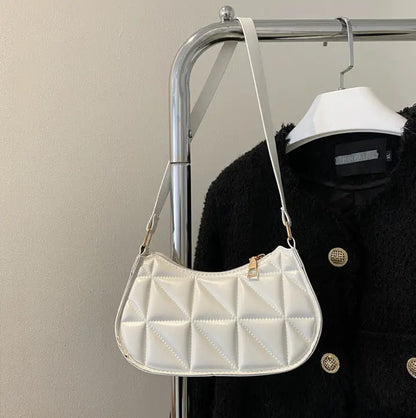 Sac bandoulière noir porté à l’épaule avec bandoulière ajustée.
