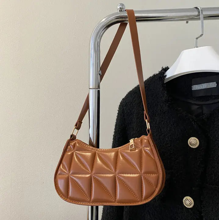 Sac bandoulière noir porté à l’épaule avec bandoulière ajustée.