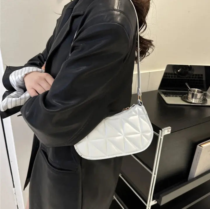 Sac bandoulière blanc porté à l’épaule, design élégant et pratique.