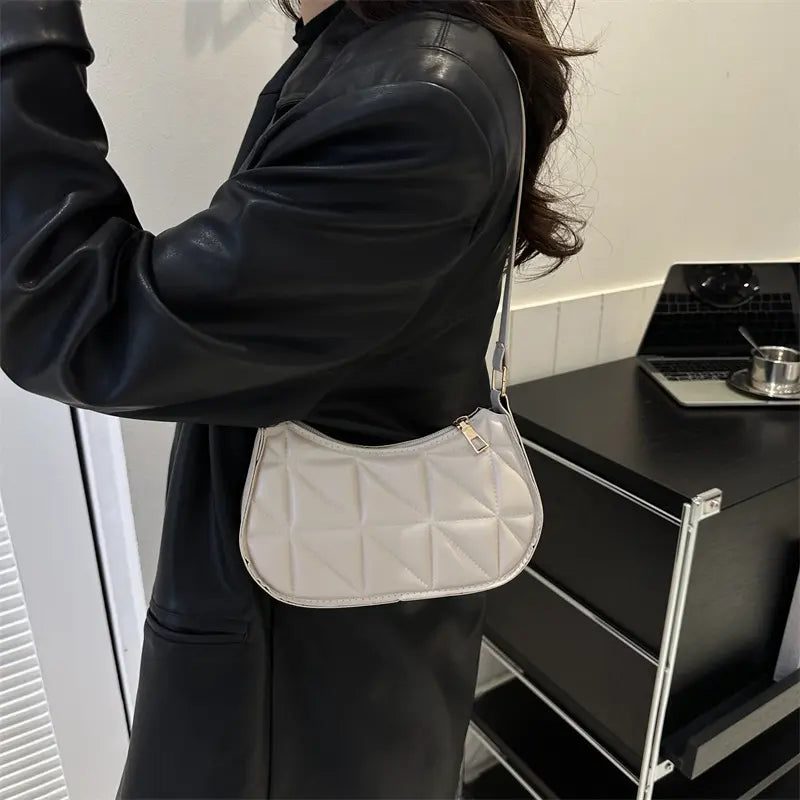 Sac bandoulière blanc porté à l’épaule, design élégant et pratique.
