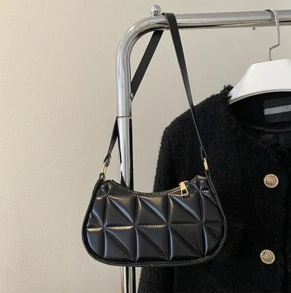 Sac bandoulière noir porté à l’épaule avec bandoulière ajustée.