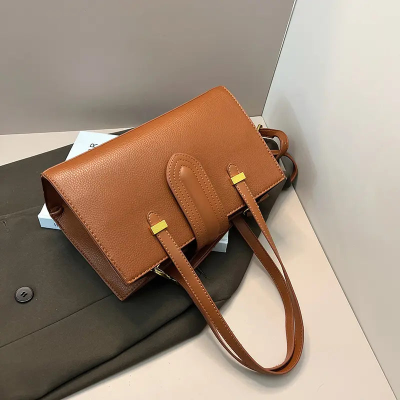 Sac cuir végan marron porté à la main, look streetwear chic.