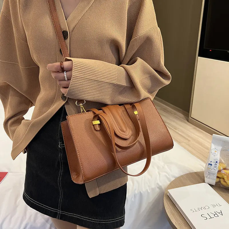 Sac cuir végan marron porté à l’épaule avec sangle ajustable.