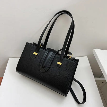 Sac cuir végan noir porté à la main, style urbain chic.