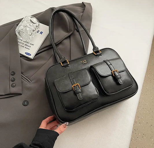 Sac à main noir élégant avec couture contrastée et bandoulière simple, vue de face.