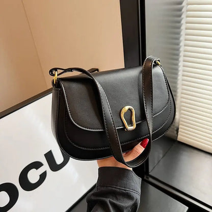 Sac à main noir porté à l’épaule avec double bretelles, style urbain chic.