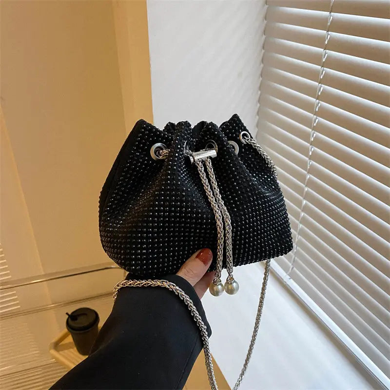 Sac seau noir porté à l’épaule avec bandoulière élégante.