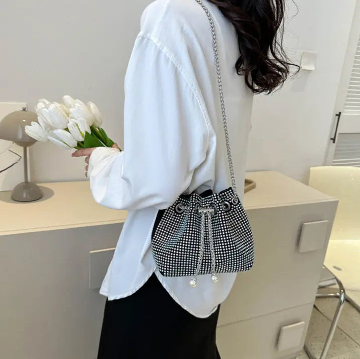 Sac seau noir porté à l’épaule avec bandoulière élégante.