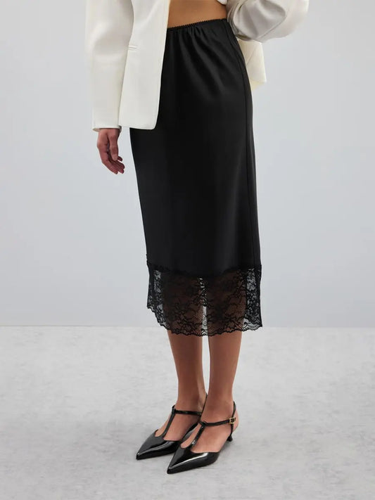 Jupe noire élégante en satin avec ourlet en dentelle, associée à une veste blanche.