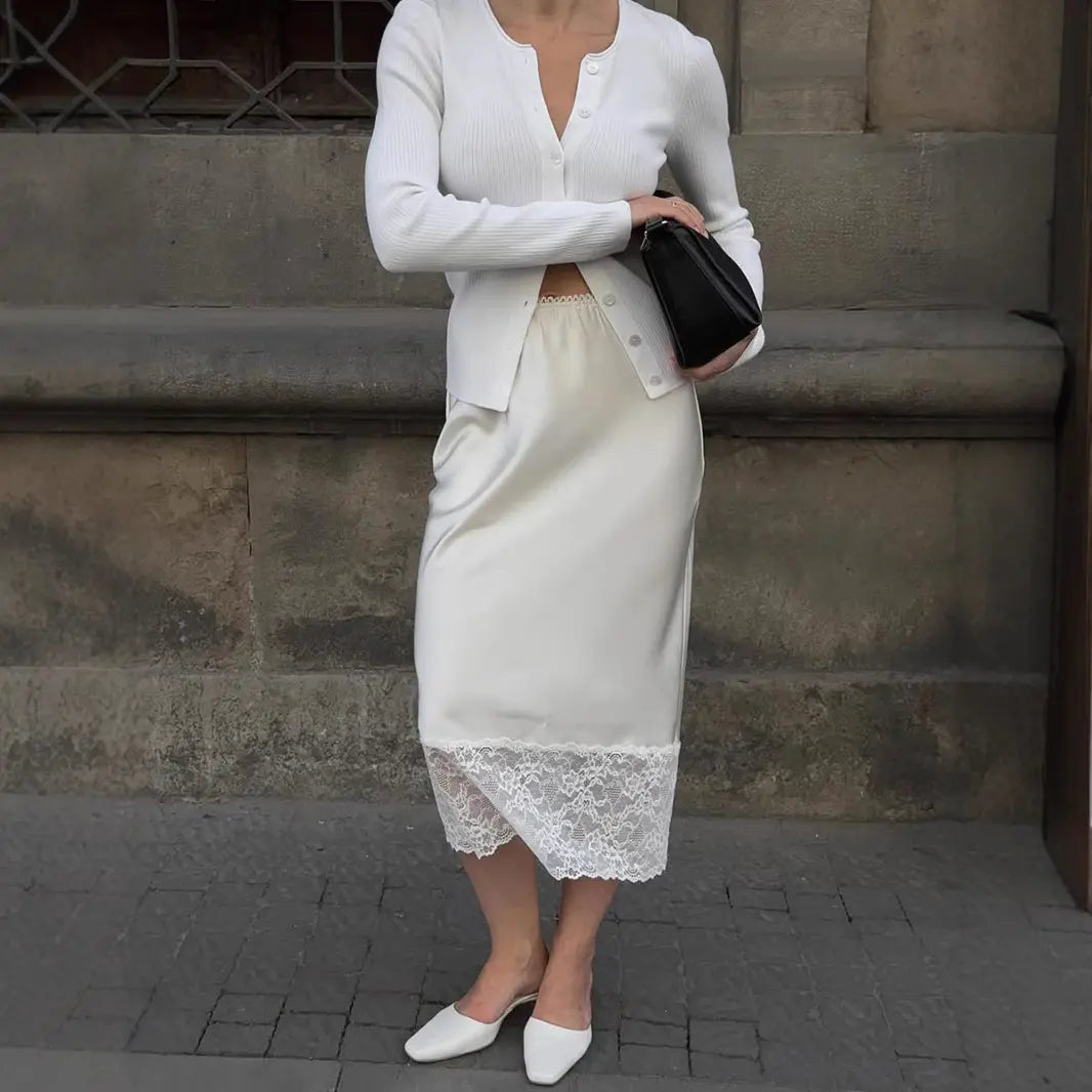 Jupe noire raffinée avec bas en dentelle, portée avec un blazer blanc pour un style intemporel.