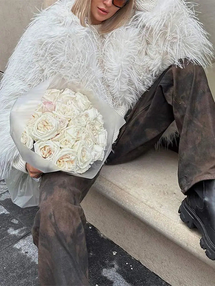 Veste blanche associée à un pantalon en cuir et accessoires chic